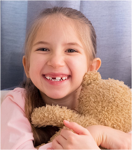 Little girl smiling and hugging teddy bear.